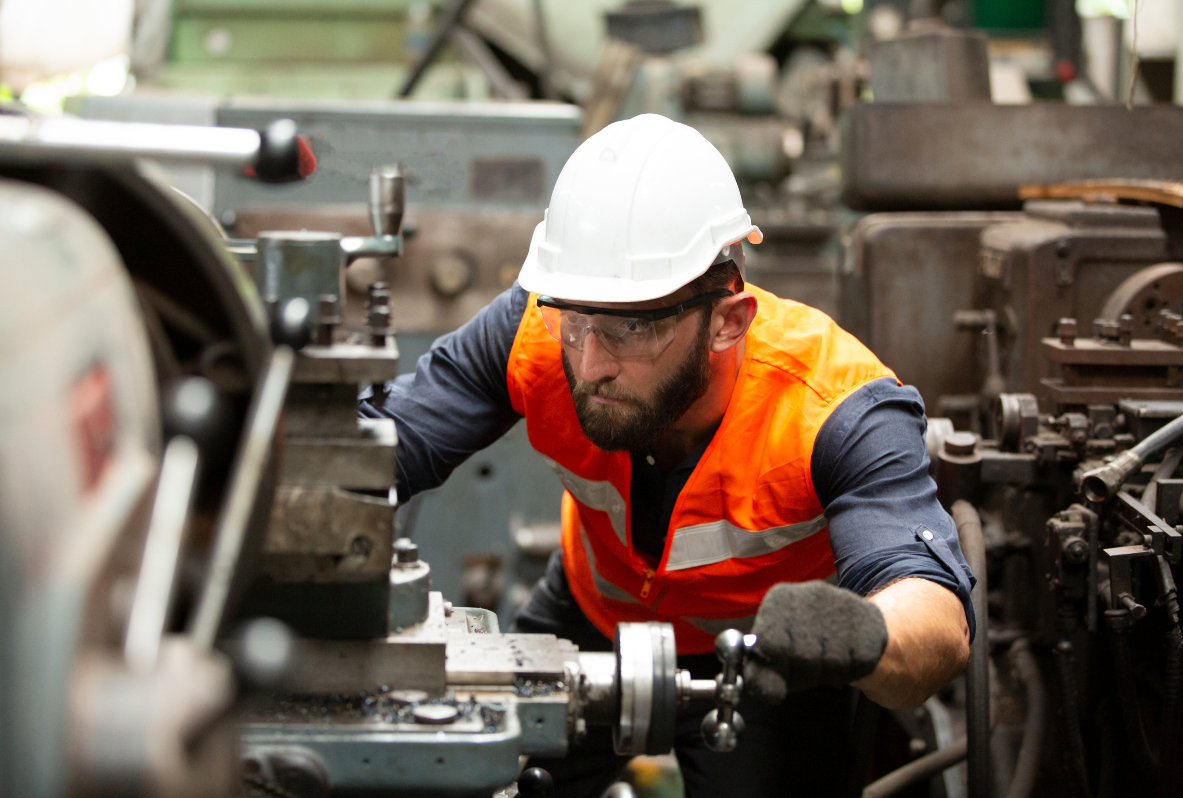 Man in work clothes and helmet operating a machine