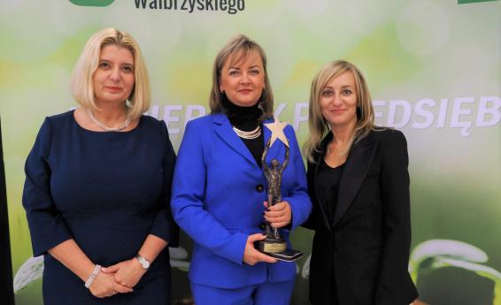Zastępca Burmistrza Dorota Pieszczuch trzyma statuetkę Gwiazdy Biznesu. Towarzyszą jej osoby wręczające nagrodę. 