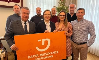Grupa przedsiębiorców  oraz Burmistrz Dariusz Kucharski trzymają baner z napisem Karta mieszkańca Dzierżoniowa.