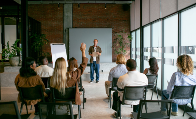 ludzie siedzą w sali wykładowej, na wprost prowadzący
