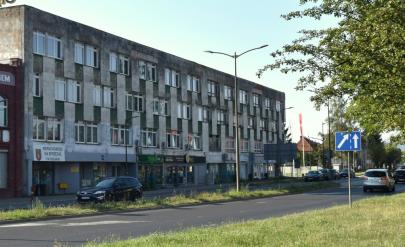 Dwupiętrowy budynek przy ulicy. Z prawej strony drzewo.