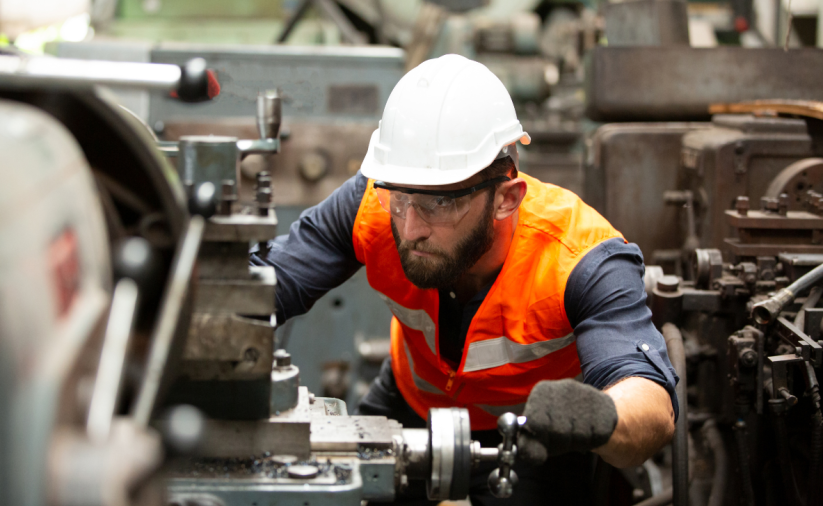 Man in work clothes and helmet operating a machine
