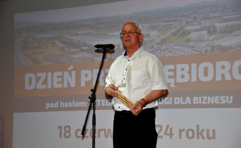 Mężczyzna stoi na scenie i przemawia do mikrofonu