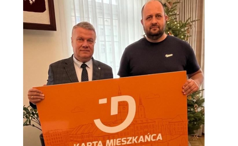 Dwie osoby trzymają pomarańczowy baner - Kartę Mieszkańca Dzierżoniowa