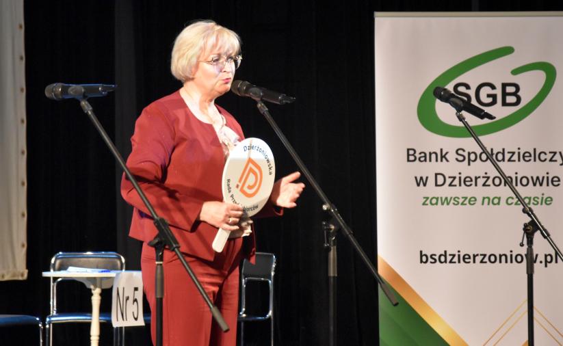 Przewodnicząca Dzierżoniowskiej Rady Przedsiębiorców przemawia na scenie podczas turnieju „Młodzi Mistrzowie Przedsiębiorczości 2026”, trzymając znak z logo Rady Przedsiębiorców. W tle baner Banku Spółdzielczego w Dzierżoniowie.
