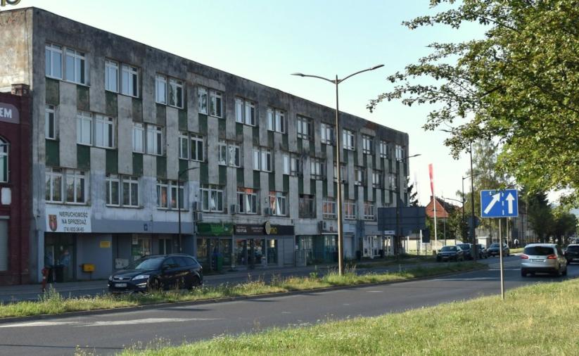 Dwupiętrowy budynek przy ulicy. Z prawej strony drzewo.