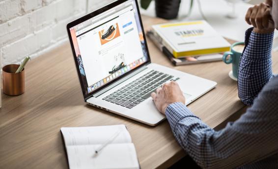 the image shows a man sitting in front of a laptop