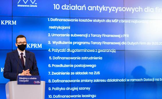 Zdjęcie przedstawia premiera Mateusza Morawieckiego na tle slajdu 10 działań antykryzysowych dla firm. Źródło: KPRM