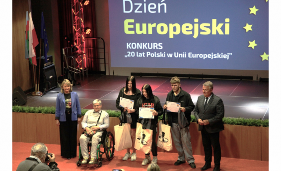 Dzień Europejski - 9 maja 2024 roku. Przed sceną stoi grupa osób. Przedstawiciele Urzędu Miasta, uczniów oraz zaproszony gość Janina Ochojska.