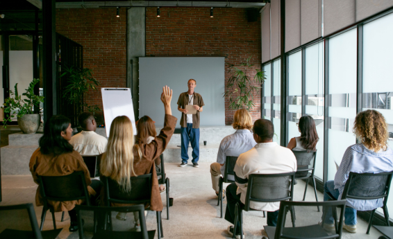 People are sitting in a lecture hall, facing the presenter.