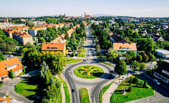 A bird's eye view of Dzierżoniów – a roundabout in the foreground, urban development surrounded by greenery and a view of the city center and hills in the distance.